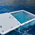 Anti Jellyfish Pool and Inflatable platform. White products in blue sea. Sunny day.