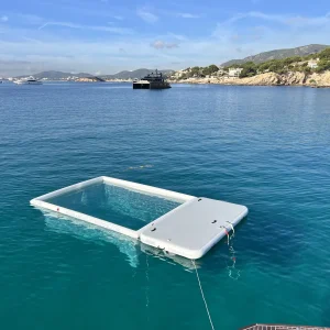 White wnti Jellyfish Pool and Inflatable Dock tied to the boat. Blue Sea. Sunny sky.