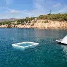 Sea Pool tied to a boat. Pool is white, sea is blue and a sunny sky.